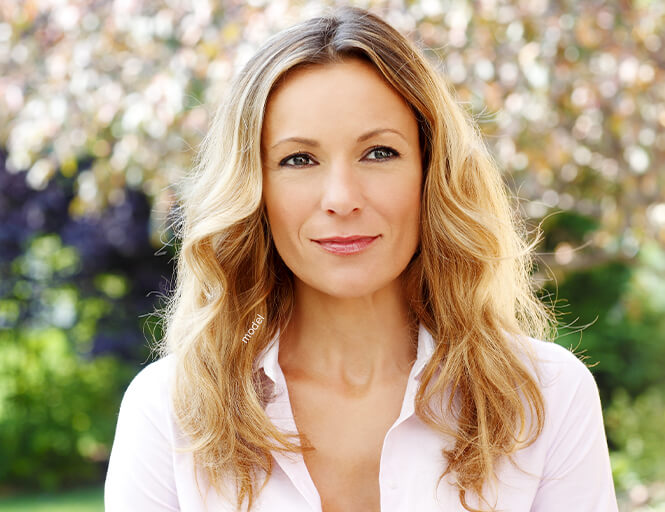 Attractive blond mature woman underneath flowering tree.