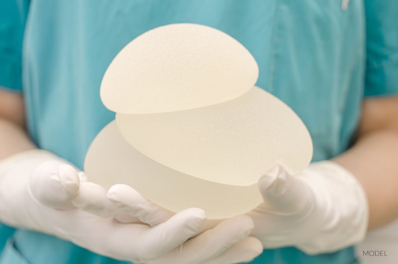 Doctor holding a stack of breast implants