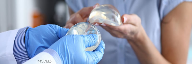 Plastic surgeon and patient holding breast implants