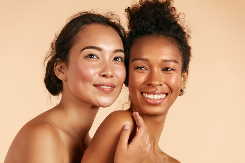 Two women embracing, smiling, with minimal makeup.