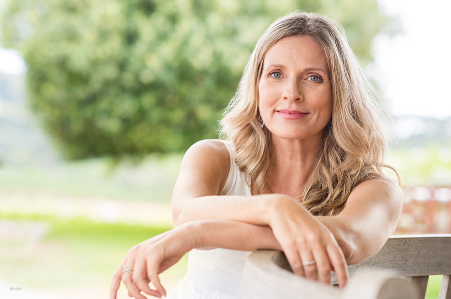 attractive, middle aged blonde woman sits outside on a bench